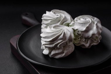 Koyu beton bir arka planda leziz, renkli bir marşmelov. Yemek masası için sağlıklı tatlılar.