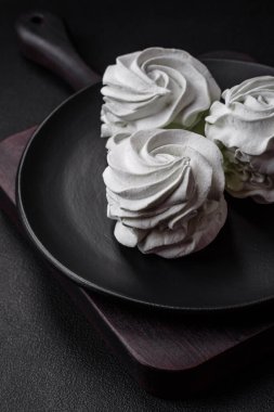 Koyu beton bir arka planda leziz, renkli bir marşmelov. Yemek masası için sağlıklı tatlılar.