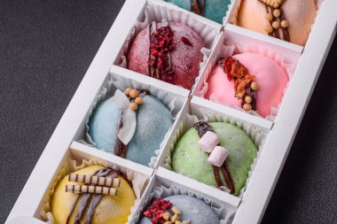 Lezzetli rengarenk mochi tatlılar ya da pirinç hamurlu dondurma ve koyu beton arka planda karton bir kutuda malzemeler.