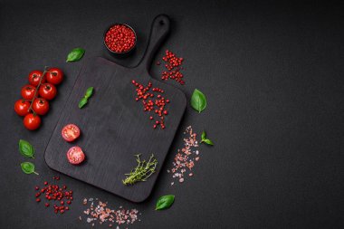 Koyu beton zeminde domates, tuz, baharat ve otlar pişirmek için gerekli malzemeler.