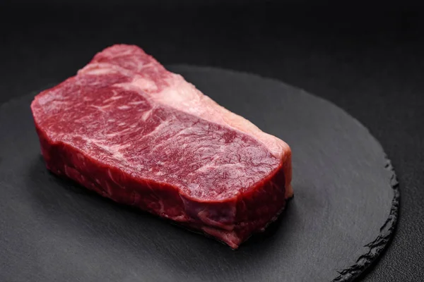 濃いコンクリートの背景に塩 スパイス ハーブの新鮮な生牛ストライプステーキ — ストック写真
