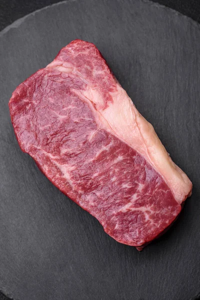 濃いコンクリートの背景に塩 スパイス ハーブの新鮮な生牛ストライプステーキ — ストック写真