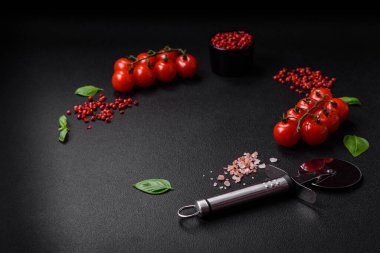 Koyu beton zeminde domates, tuz, baharat ve otlar pişirmek için gerekli malzemeler.