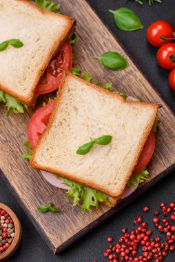 Lezzetli sandviç, tost, jambon, domates, peynir ve tuzlu, baharatlı ve çimento kaplı marul.