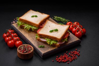 Lezzetli sandviç, tost, jambon, domates, peynir ve tuzlu, baharatlı ve çimento kaplı marul.