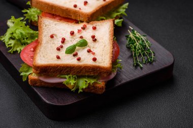 Lezzetli sandviç, tost, jambon, domates, peynir ve tuzlu, baharatlı ve çimento kaplı marul.