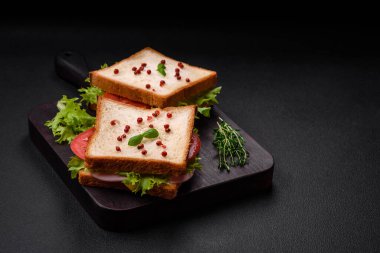 Lezzetli sandviç, tost, jambon, domates, peynir ve tuzlu, baharatlı ve çimento kaplı marul.