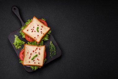 Lezzetli sandviç, tost, jambon, domates, peynir ve tuzlu, baharatlı ve çimento kaplı marul.