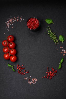 Koyu beton zeminde domates, tuz, baharat ve otlar pişirmek için gerekli malzemeler.
