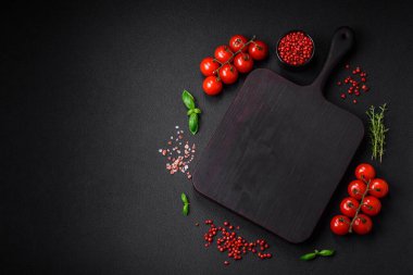 Koyu beton zeminde domates, tuz, baharat ve otlar pişirmek için gerekli malzemeler.