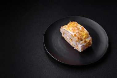 Lezzetli, taze, tatlı kremalı krema, badem cipsi, fındık ve böğürtlen dilimleri koyu beton arka planda kesilmiş.