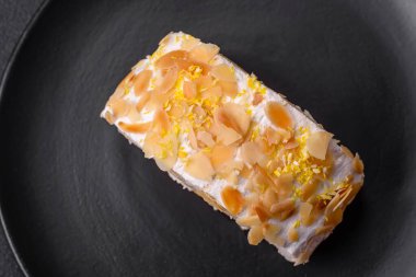 Lezzetli, taze, tatlı kremalı krema, badem cipsi, fındık ve böğürtlen dilimleri koyu beton arka planda kesilmiş.