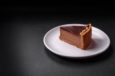 Lezzetli, taze, fındıklı çikolatalı pasta. Koyu beton arka planda dilimler halinde kesilmiş.