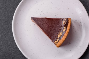 Lezzetli, taze, fındıklı çikolatalı pasta. Koyu beton arka planda dilimler halinde kesilmiş.