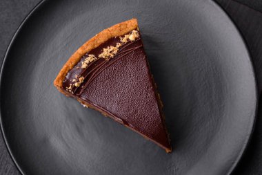 Lezzetli, taze, fındıklı çikolatalı pasta. Koyu beton arka planda dilimler halinde kesilmiş.