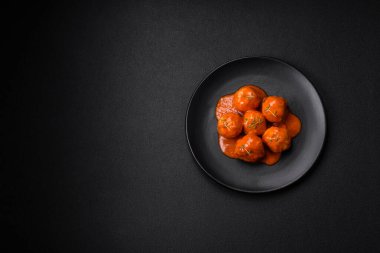 Lezzetli taze köfteler, tuz, baharat ve çimento arkaplanda bitkilerle birlikte domates sosu.