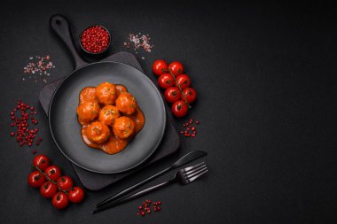 Lezzetli taze köfteler, tuz, baharat ve çimento arkaplanda bitkilerle birlikte domates sosu.