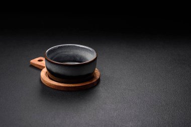 Boş yuvarlak seramik kâse, ahşap bir kesme tahtasının üzerinde kahverengi renkli koyu desenli beton arka planda.