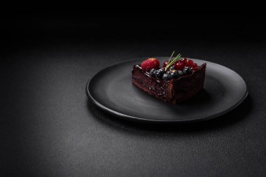 Seramik tabakta yaban mersinli, üzümlü ve ahududulu lezzetli çikolatalı kek.