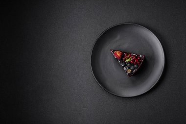 Seramik tabakta yaban mersinli, üzümlü ve ahududulu lezzetli çikolatalı kek.