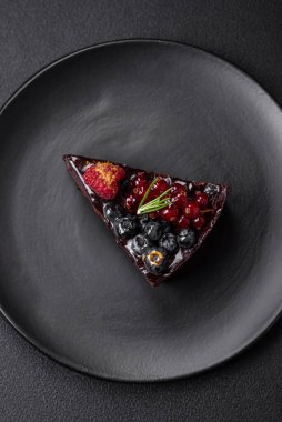 Seramik tabakta yaban mersinli, üzümlü ve ahududulu lezzetli çikolatalı kek.