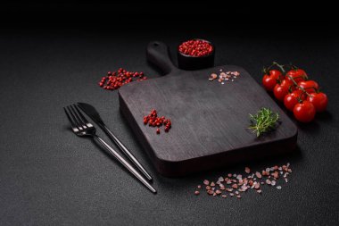 Koyu beton zeminde domates, tuz, baharat ve otlar pişirmek için gerekli malzemeler.