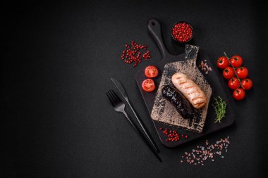 Tuz, baharat ve otlarla ızgara yapılmış lezzetli, sulu sosisler koyu beton bir arka planda.