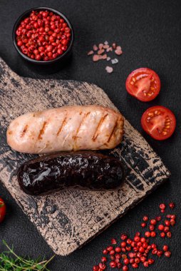 Tuz, baharat ve otlarla ızgara yapılmış lezzetli, sulu sosisler koyu beton bir arka planda.