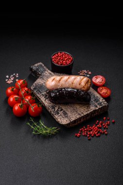 Tuz, baharat ve otlarla ızgara yapılmış lezzetli, sulu sosisler koyu beton bir arka planda.