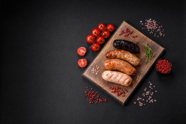 Tuz, baharat ve otlarla ızgara yapılmış lezzetli, sulu sosisler koyu beton bir arka planda.