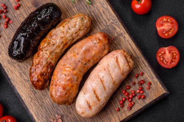 Tuz, baharat ve otlarla ızgara yapılmış lezzetli, sulu sosisler koyu beton bir arka planda.