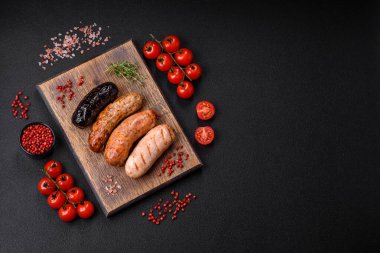 Tuz, baharat ve otlarla ızgara yapılmış lezzetli, sulu sosisler koyu beton bir arka planda.