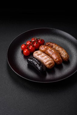 Tuz, baharat ve otlarla ızgara yapılmış lezzetli, sulu sosisler koyu beton bir arka planda.