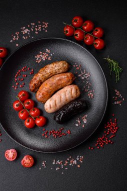 Tuz, baharat ve otlarla ızgara yapılmış lezzetli, sulu sosisler koyu beton bir arka planda.