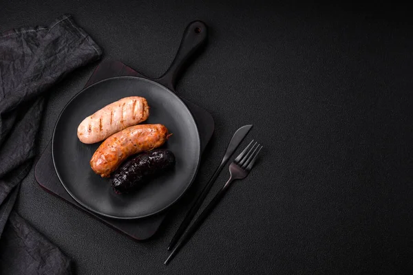 stock image Delicious juicy sausages of several varieties grilled with salt, spices and herbs on a dark concrete background