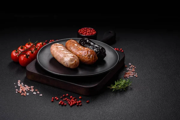 stock image Delicious juicy sausages of several varieties grilled with salt, spices and herbs on a dark concrete background