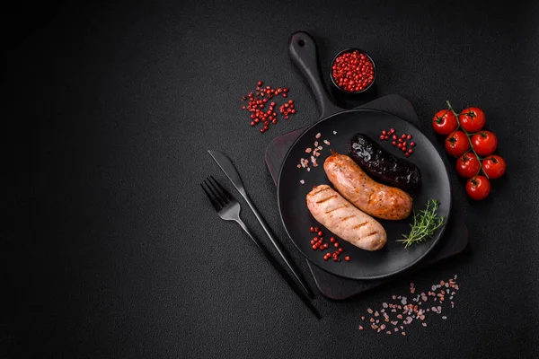 stock image Delicious juicy sausages of several varieties grilled with salt, spices and herbs on a dark concrete background