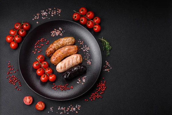 stock image Delicious juicy sausages of several varieties grilled with salt, spices and herbs on a dark concrete background