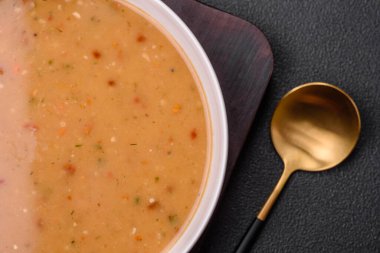 Havuçlu, biberli, patatesli ve soğanlı nefis taze sebze çorbası. Beyaz seramik tabakta, koyu beton arka planda.