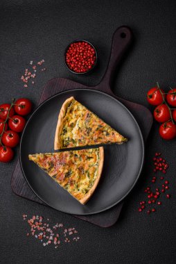 Brokolili, peynirli, baharatlı ve otlu lezzetli taze kiş koyu beton bir arka planda parçalara bölünmüş.