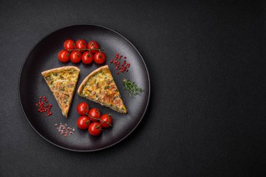 Brokolili, peynirli, baharatlı ve otlu lezzetli taze kiş koyu beton bir arka planda parçalara bölünmüş.