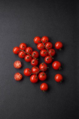 Koyu betondan bir arka planda vejetaryen yemeği pişirmek için dallarda lezzetli taze domatesler.