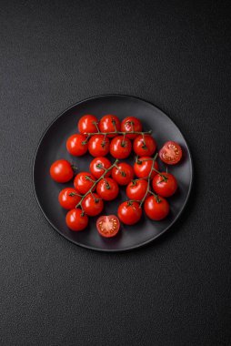Koyu betondan bir arka planda vejetaryen yemeği pişirmek için dallarda lezzetli taze domatesler.