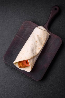 Tavuk nugget, domates, marul, tuz ve baharatlı sos ve koyu beton arka planda lezzetli rulo.