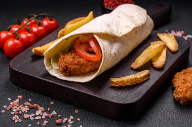 Tavuk nugget, domates, marul, tuz ve baharatlı sos ve koyu beton arka planda lezzetli rulo.