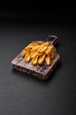 Lezzetli, çıtır çıtır patatesler, tuzlu ve baharatlı beton bir arka planda. Fast food