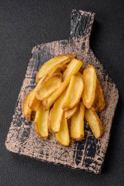 Lezzetli, çıtır çıtır patatesler, tuzlu ve baharatlı beton bir arka planda. Fast food