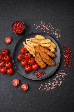 Koyu beton arka planda tuz ve baharatla ekilmiş lezzetli çıtır tavuk nuggetları.