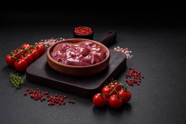 Taze çiğ tavuk veya seramik tabakta hindi ciğeri. Koyu beton arka planda tuz, baharat ve otlarla birlikte.