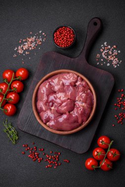 Taze çiğ tavuk veya seramik tabakta hindi ciğeri. Koyu beton arka planda tuz, baharat ve otlarla birlikte.